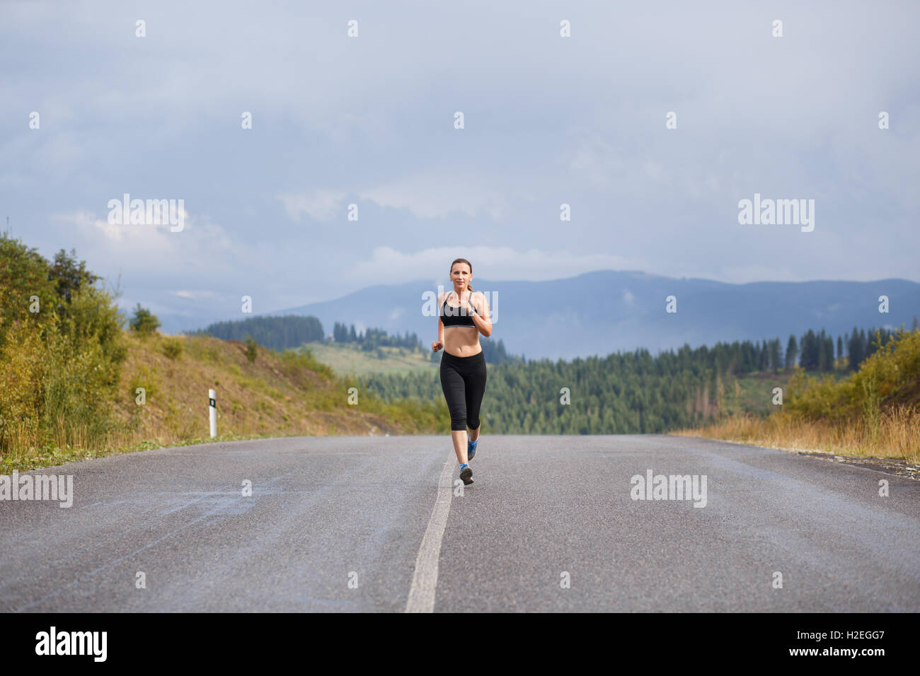 Young slim woman in sportswear jogging on the road in mountains Stock ...
