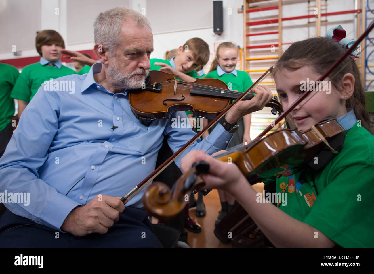 Labour leader Jeremy Corbyn is given a violin lesson by 10 year old Jessica Kelly during a visit to Faith Primary School in Liverpool, where he met children taking part in the In Harmony project, which is supported by the Royal Liverpool Philharmonic Orchestra and is helping school children learn to play musical instruments. Stock Photo