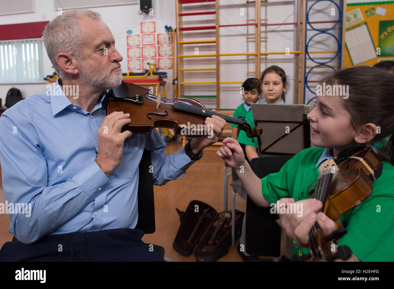 Labour leader Jeremy Corbyn is given a violin lesson by 10 year old Jessica Kelly during a visit to Faith Primary School in Liverpool, where he met children taking part in the In Harmony project, which is supported by the Royal Liverpool Philharmonic Orchestra and is helping school children learn to play musical instruments. Stock Photo