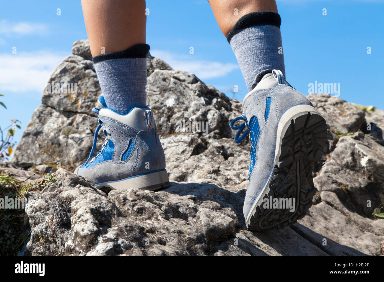 Close up of hiking boots and legs climbing up rocky trail Stock Photo