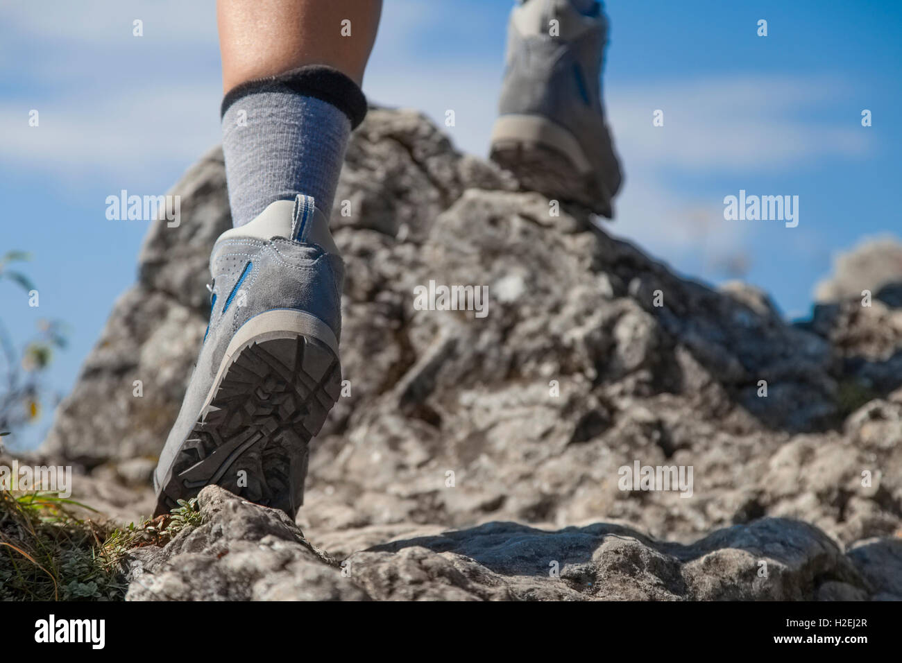 Close up of hiking boots and legs climbing up rocky trail Stock Photo