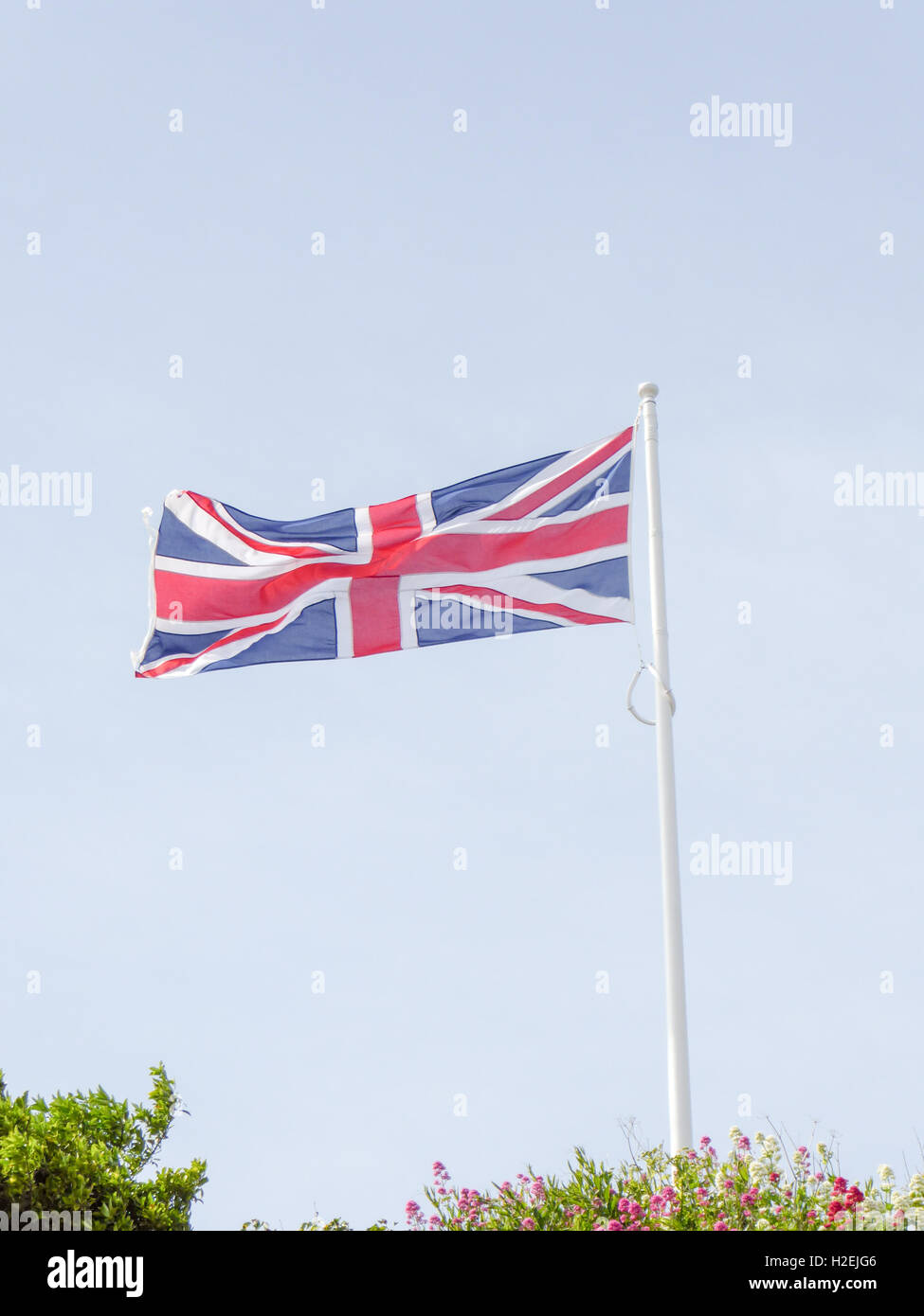 Union Jack flag flying over a blue sky background Stock Photo - Alamy