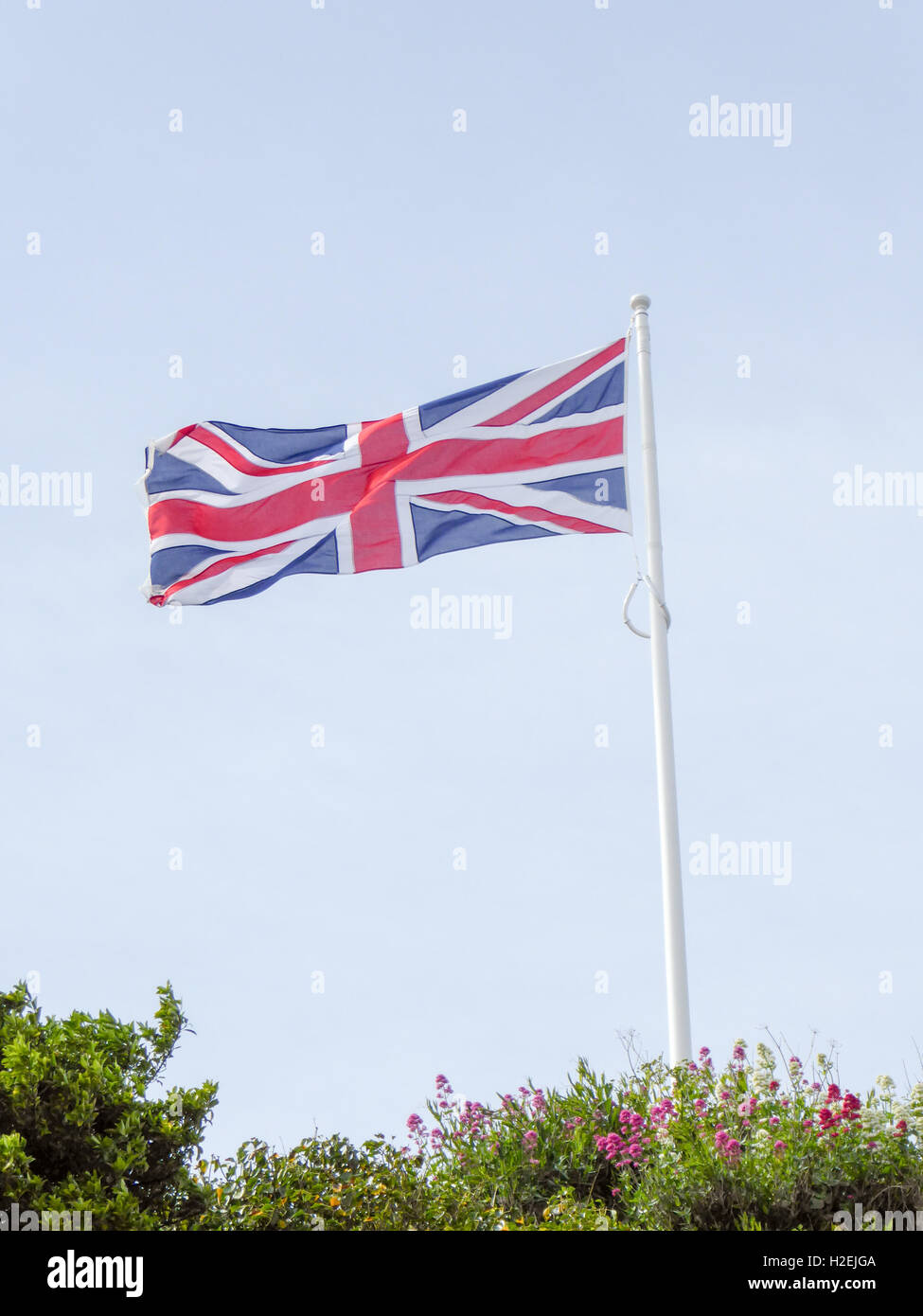Union Jack flag flying over a blue sky background Stock Photo - Alamy