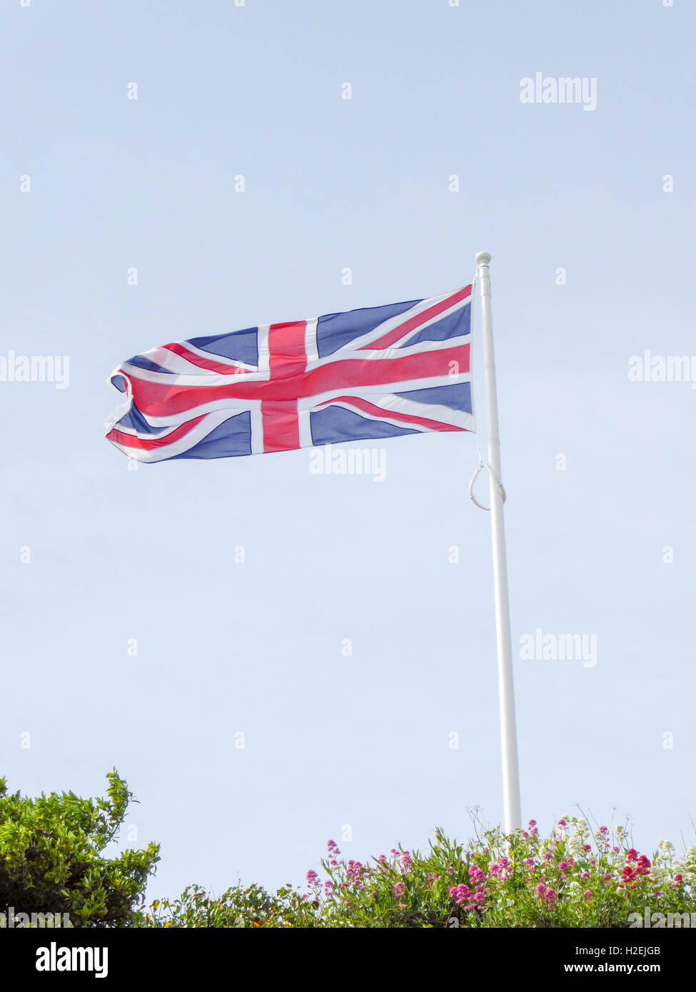 Union Jack flag flying over a blue sky background Stock Photo - Alamy
