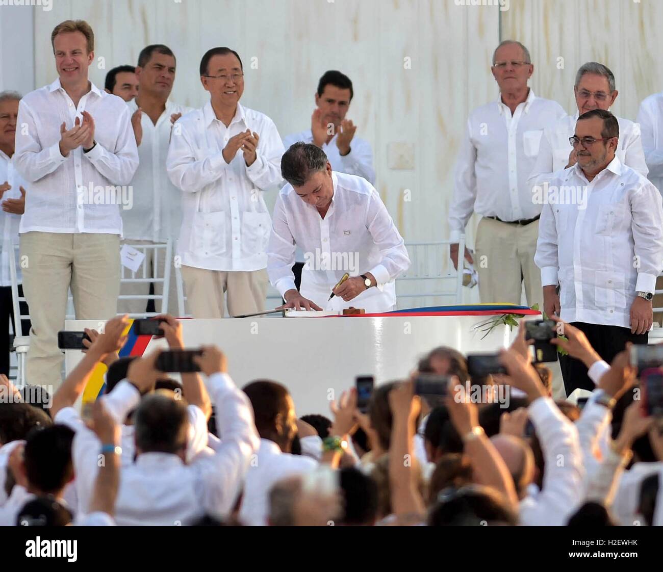 Cartagena, Colombia. 26th September, 2016. Colombian President Juan Manuel Santos, signs the peace agreement with the commander of the FARC Rodrigo Londono, right, as world leaders look on during a ceremony September 26, 2016 in Cartagena, Colombia. The agreement ends 50 years of armed conflict between the government and leftist rebel forces. Credit:  Planetpix/Alamy Live News Stock Photo