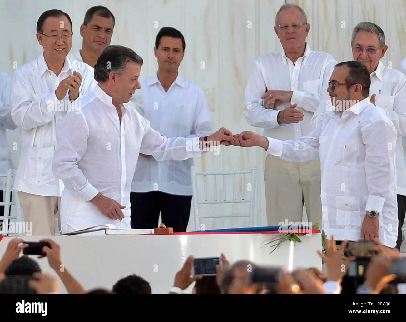 Cartagena, Colombia. 26th September, 2016. Colombian President Juan Manuel Santos, hands the pen to commander of the FARC Rodrigo Londono, right, as world leaders look on during a signing ceremony September 26, 2016 in Cartagena, Colombia. The agreement ends 50 years of armed conflict between the government and leftist rebel forces. Credit:  Planetpix/Alamy Live News Stock Photo