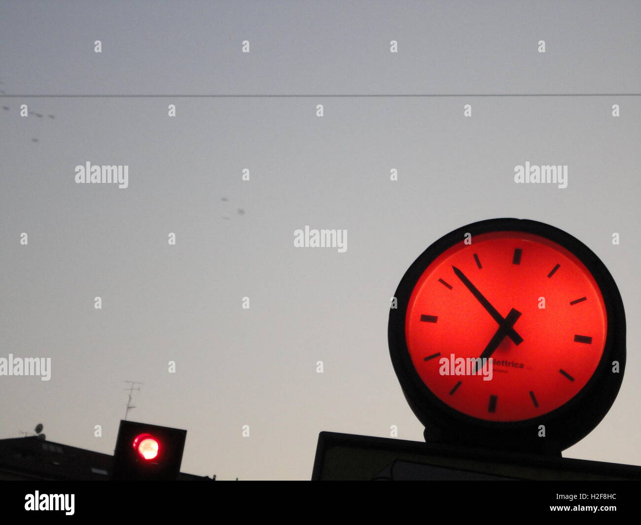 fun funky fluorescent lightened red clock against a clear blue sky at
