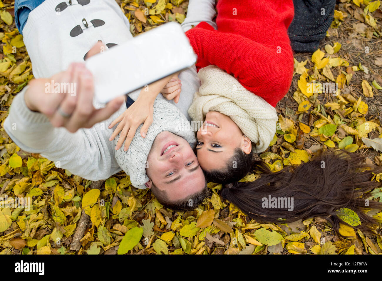 Beautiful couple in autumn park lying on the ground Stock Photo - Alamy