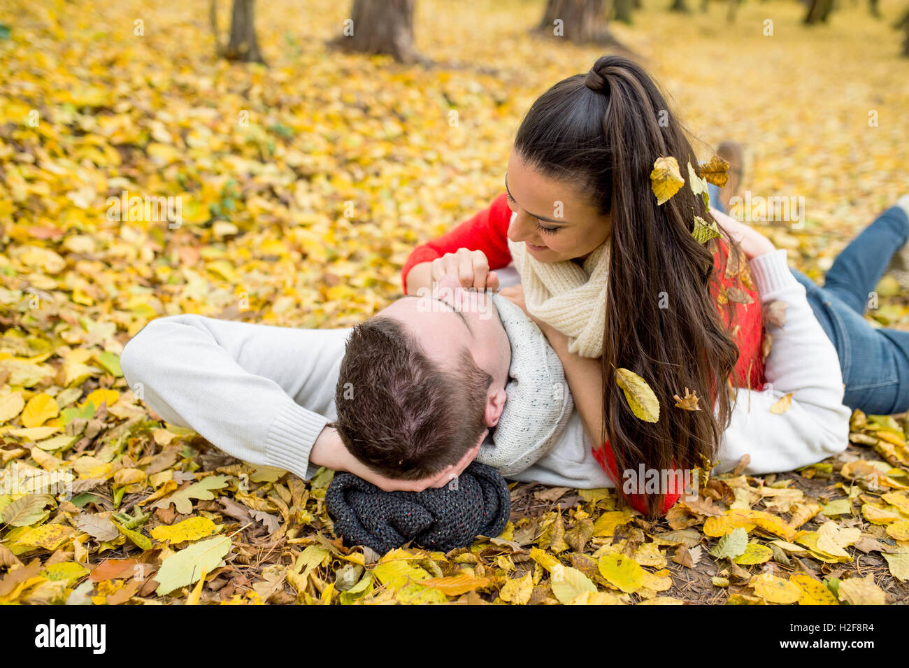 Beautiful couple in autumn park lying on the ground Stock Photo - Alamy