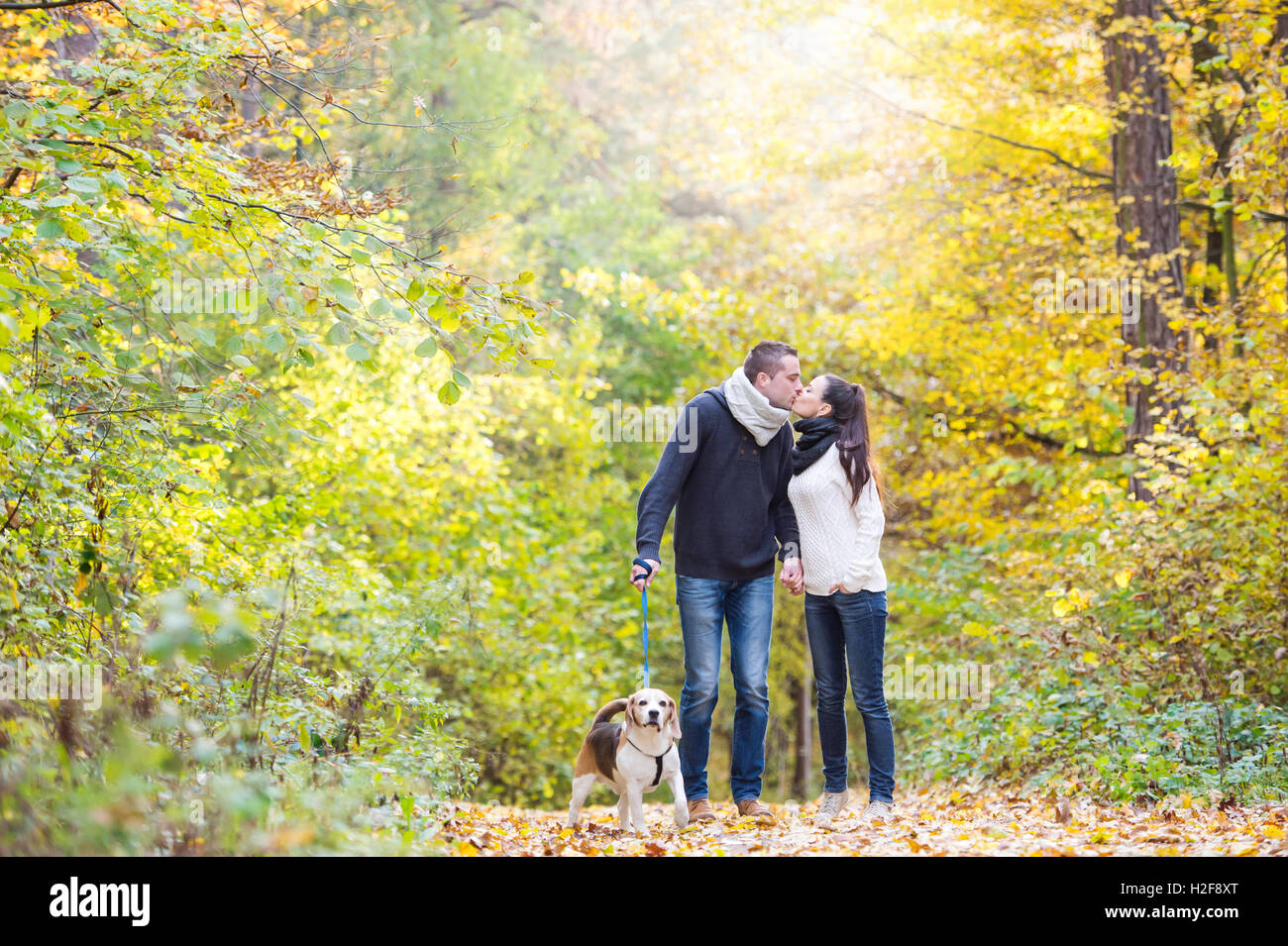 Young couple with dog on a walk in autumn forest Stock Photo