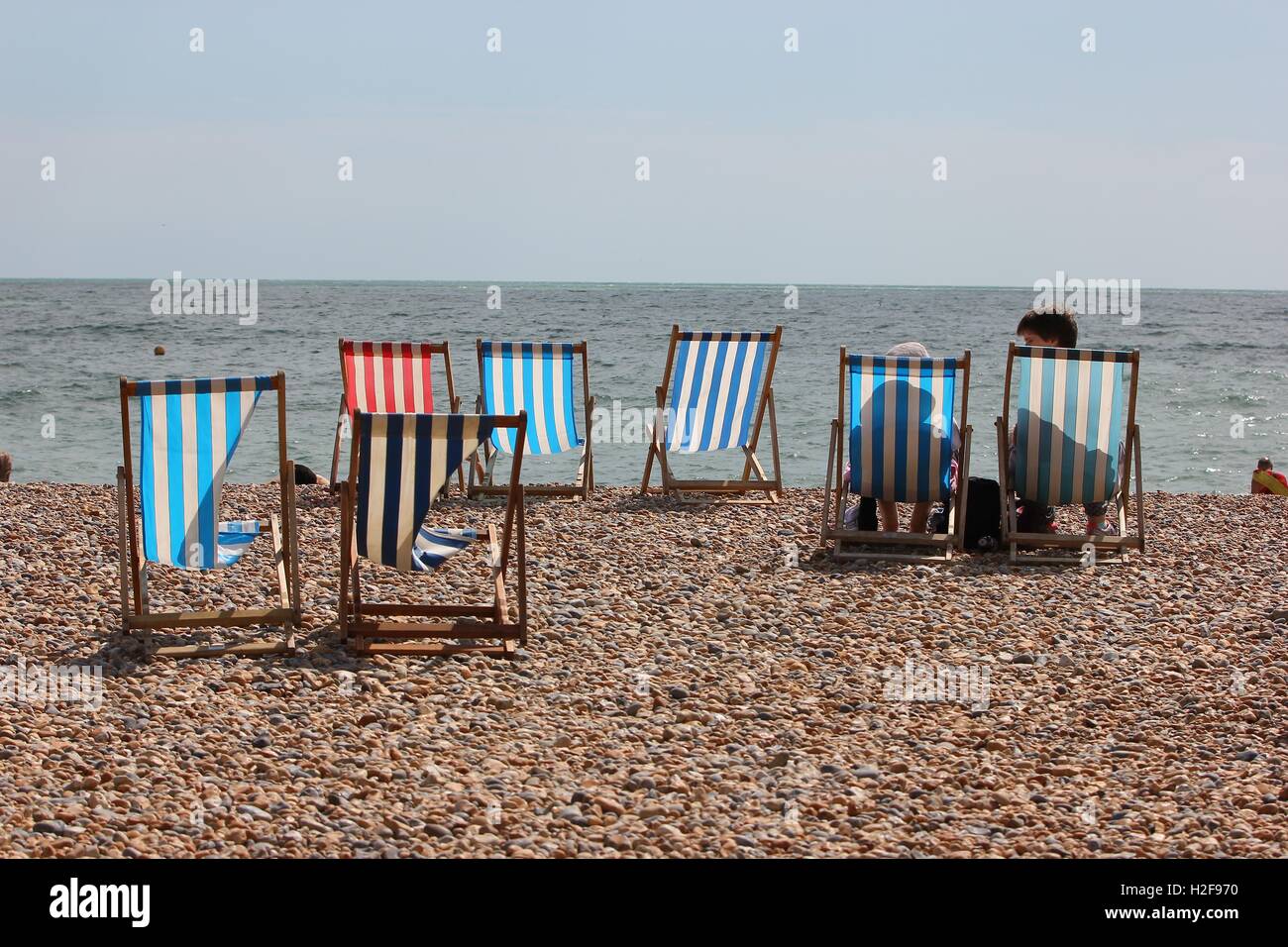 Colorful striped beach deck chairs on the cobbled beach front hires