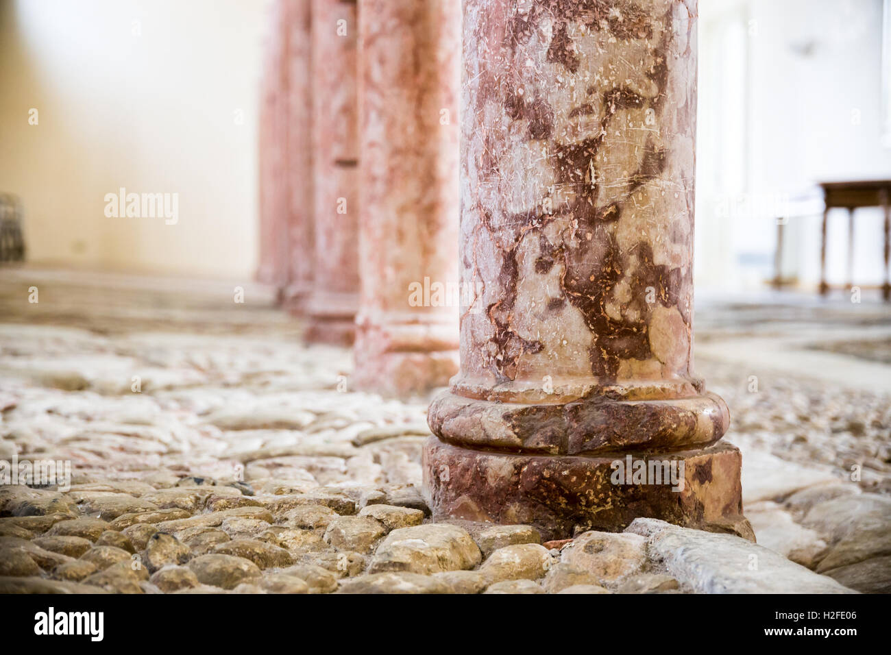 Antique red marble columns resting on stone floor. Stock Photo