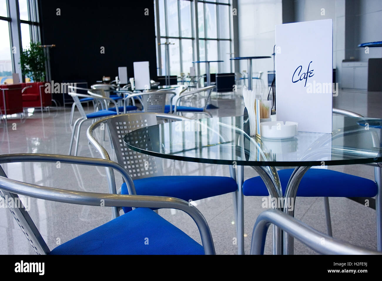 Modern cafe interior with glassy tables, large windows, stone floor and reflections. Stock Photo