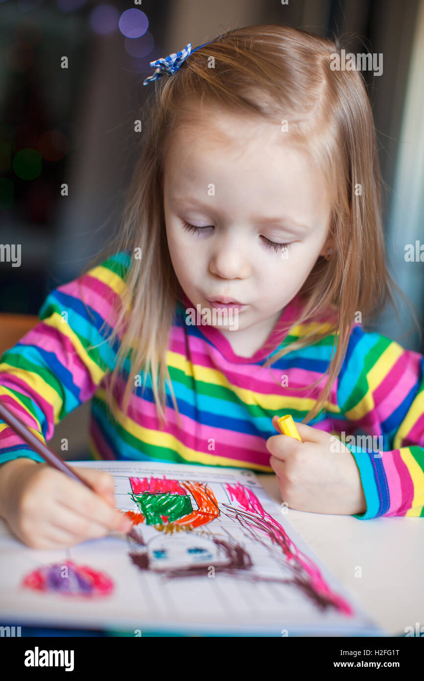 Little cute girl painting with pencils while sitting at her table Stock