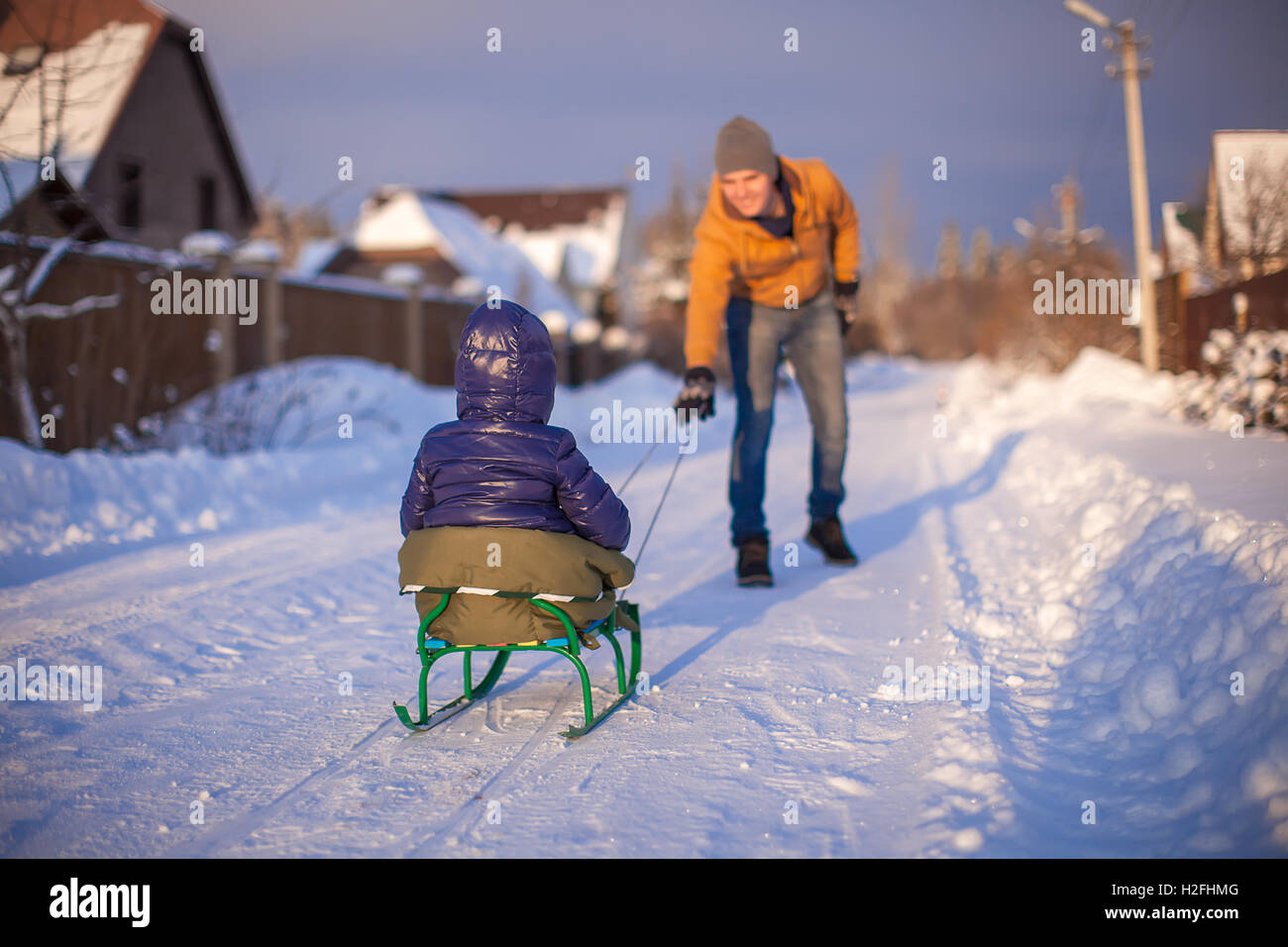 Young father sledding his little daughter on a sled in the snow