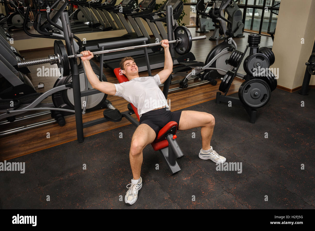 Young man doing Barbell Incline Bench Press workout in gym Stock Photo