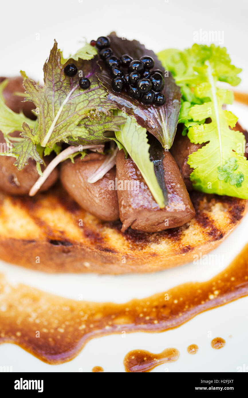 Village public house menu dish. A plate with cooked meat, sliced and arranged on  a slice of bread, with vegetable garnish. Stock Photo