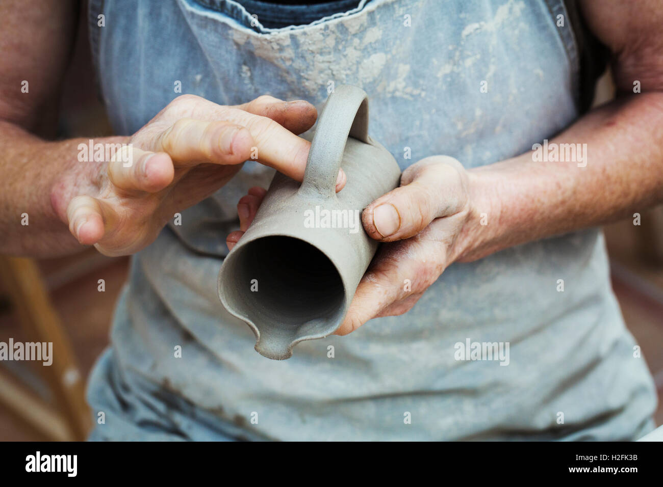 A potter handling a wet clay pot, smoothing the outside and preparing it for kiln firing. Stock Photo