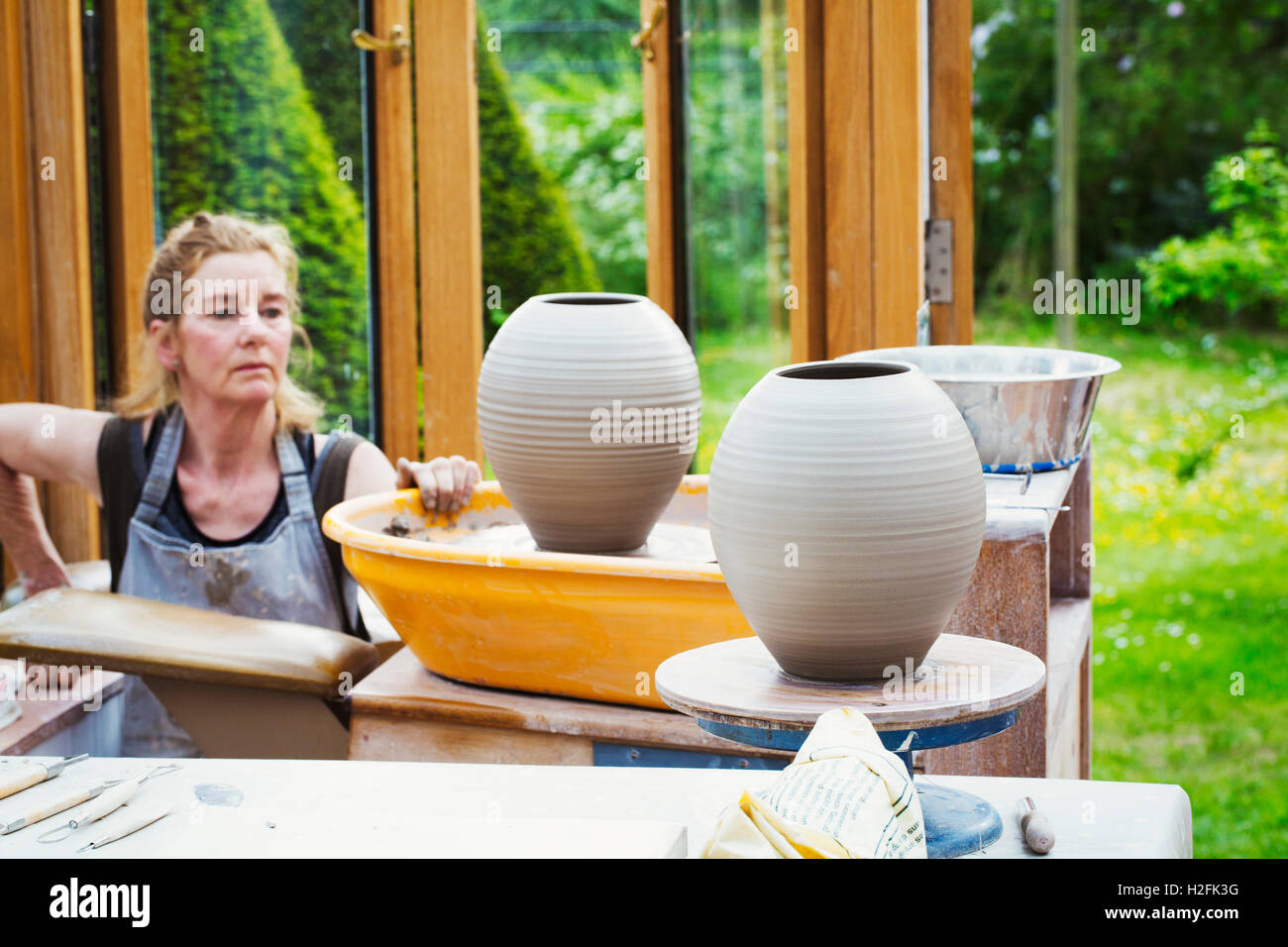 A potter examining her prefired clay pots drying before kiln firing