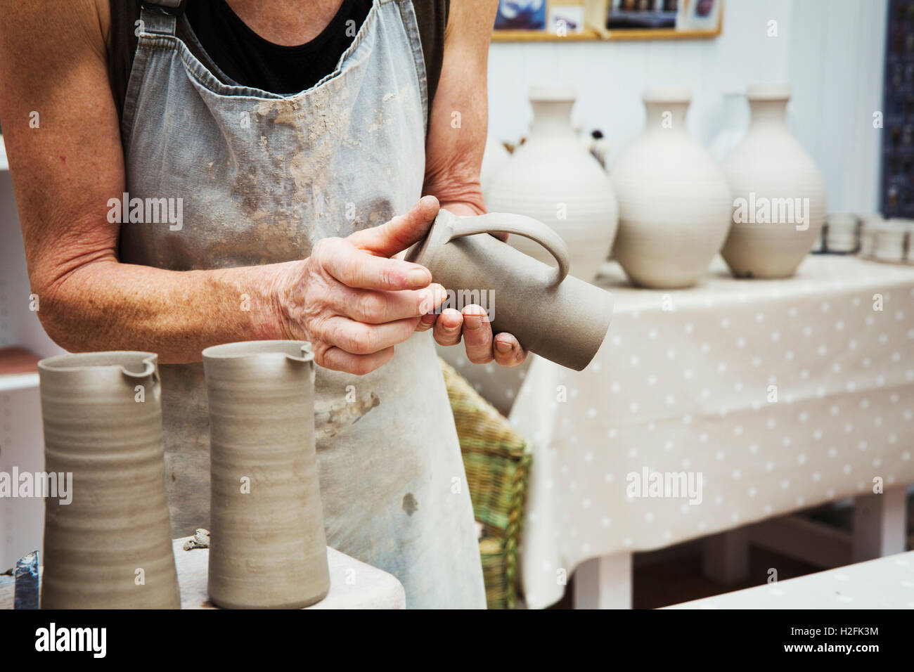 A potter handling a wet clay pot, smoothing the bottom and preparing it for kiln firing. Stock Photo