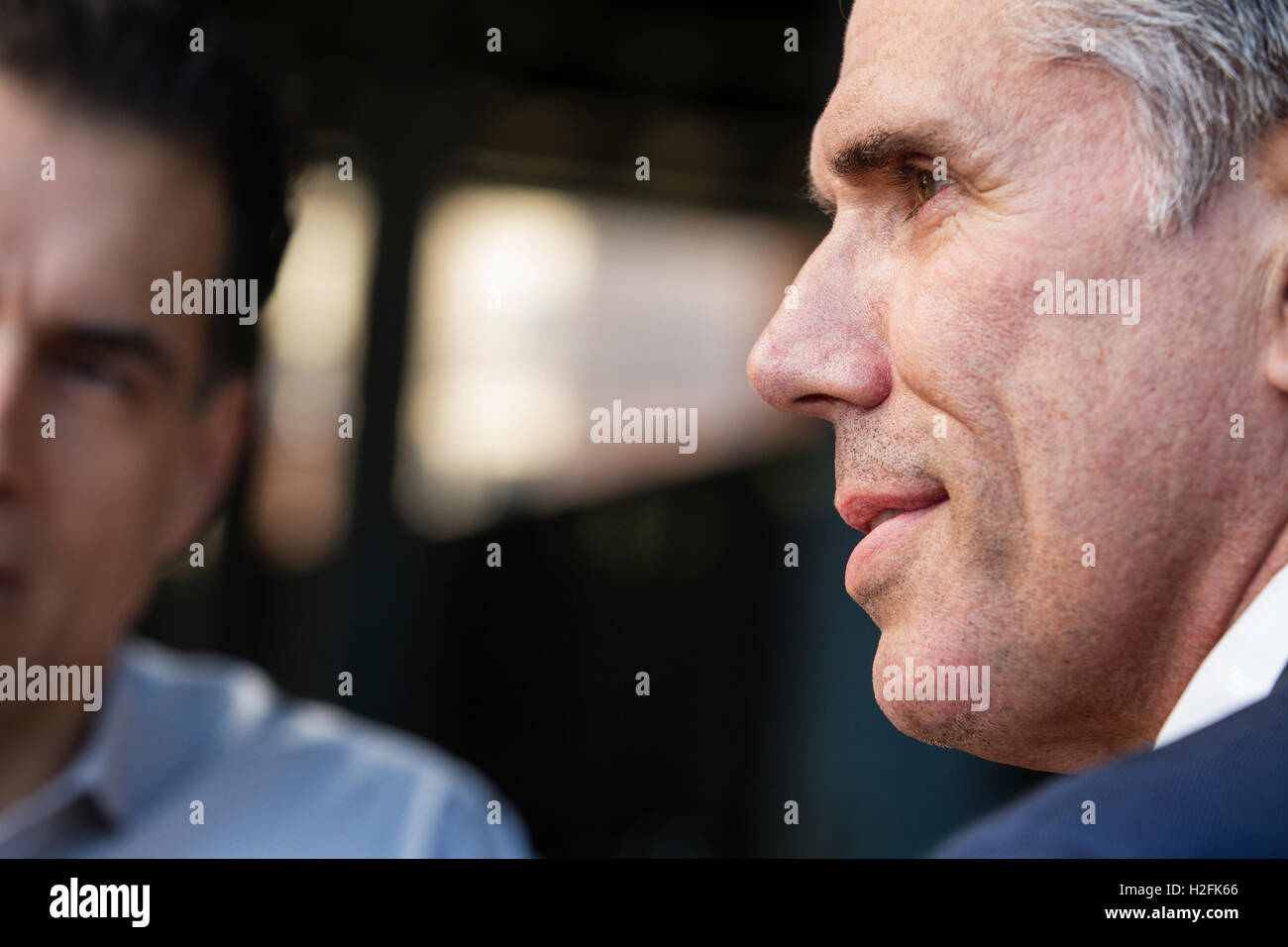 Two men on  a street, one looking sideways and one partly visible, head and shoulders, Stock Photo