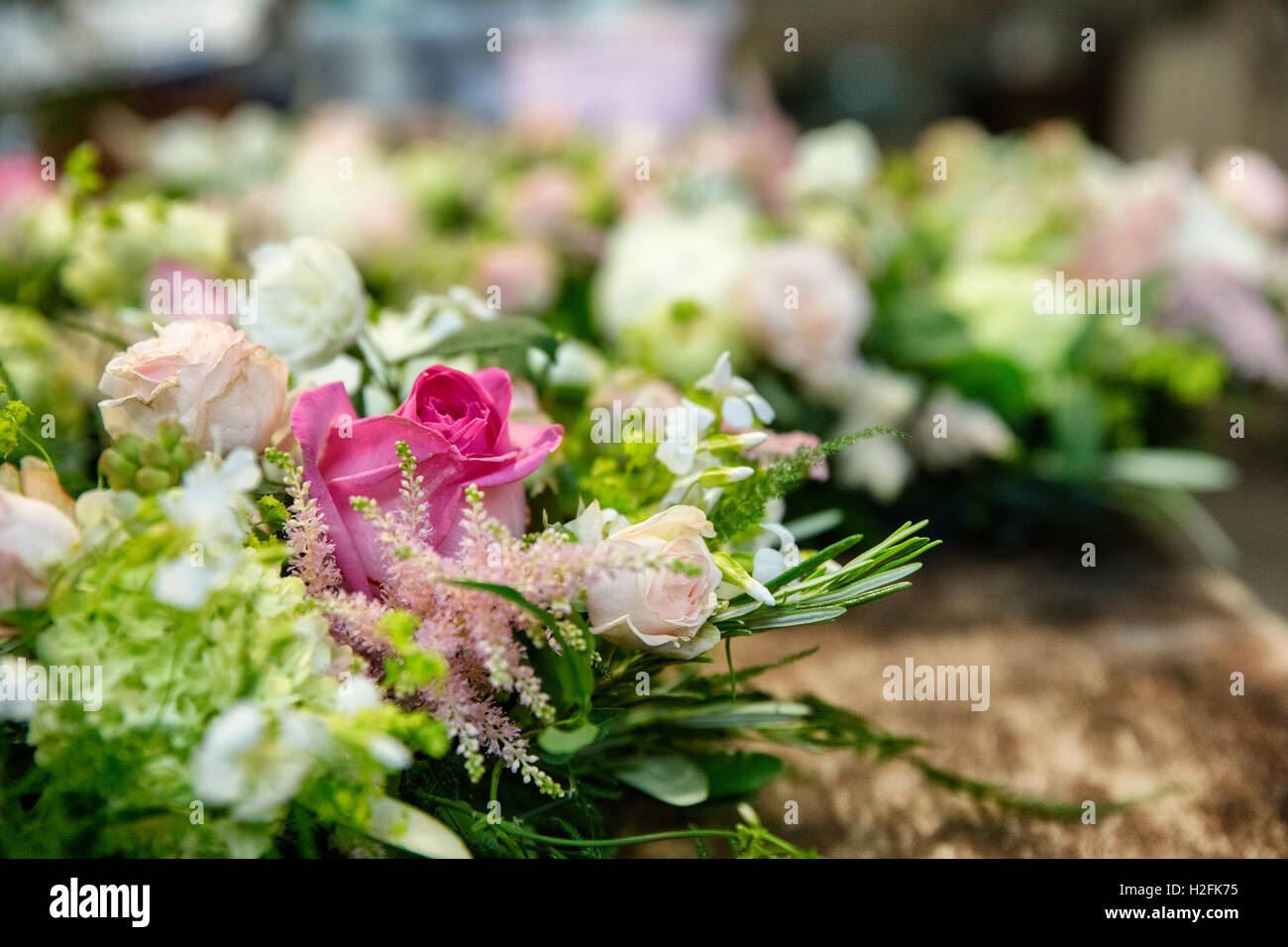 Close up of arrangements on  a workbench. Pink and white flowers with green foliage. Stock Photo