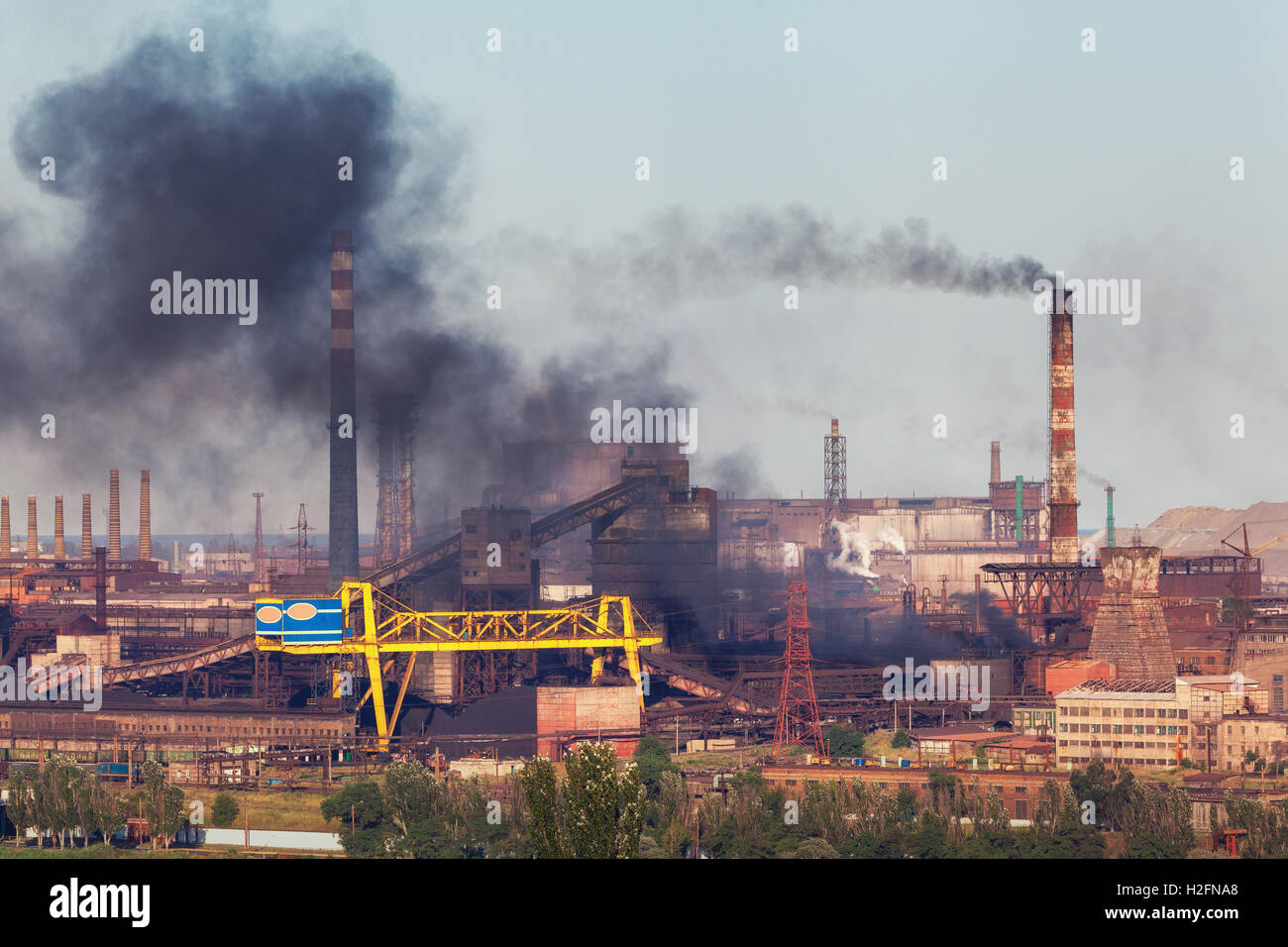 Steel factory with smog at sunset. Pipes with black smoke. Metallurgical plant. steelworks, iron works. Heavy industry. Industri Stock Photo