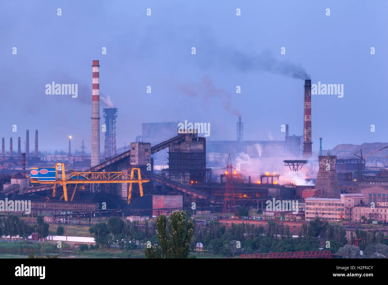 Metallurgical plant at night. Steel factory with smokestacks. Steelworks, iron works. Heavy industry at twilight. Air pollution Stock Photo