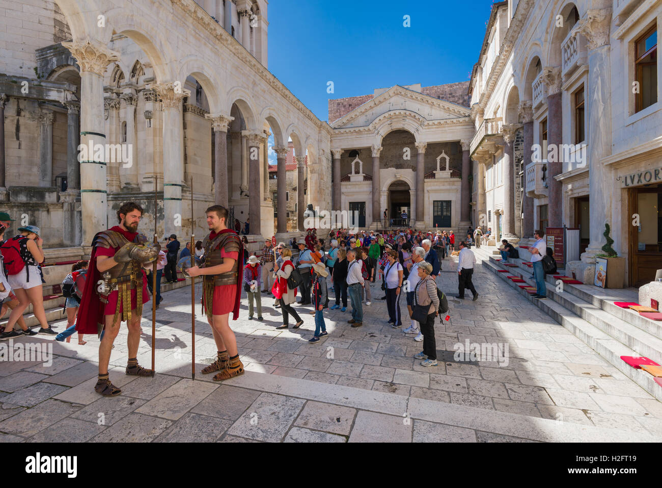Two men dressed as roman soldiers stand in the Peristil in Diocletian's Palace where tourists take photos and admire the history Stock Photo