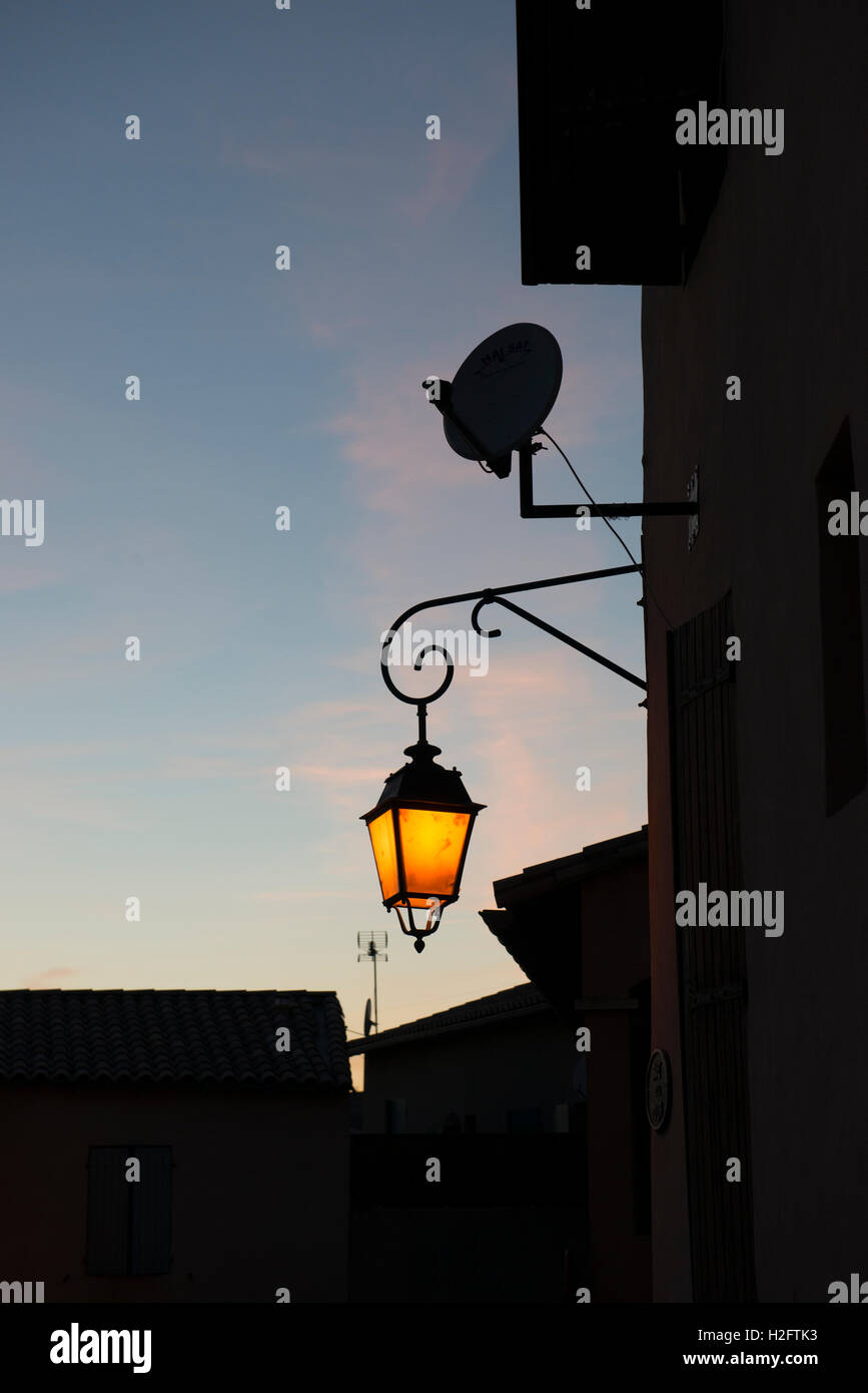 Shining street lantern at dusk, St. Gilles, Gard department, southern France Stock Photo