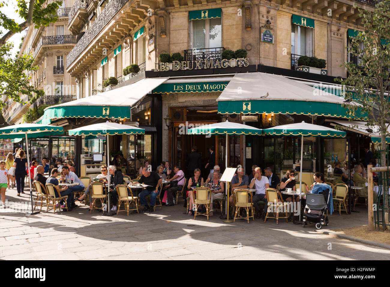 Patrons sit outside the Les Deux Magots café in Saint-Germain-des-Prés, Paris, France. Stock Photo