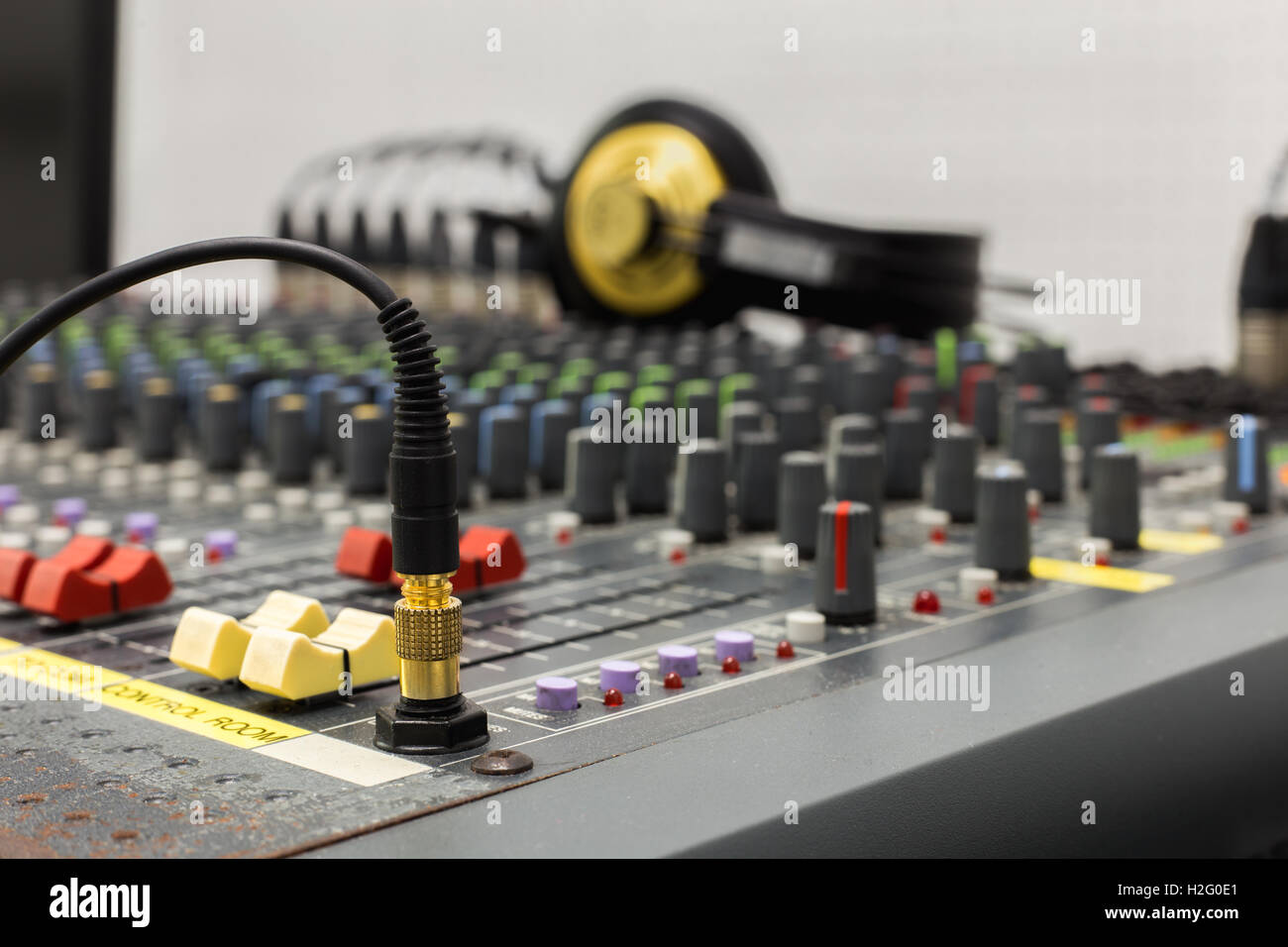 Photograph of a DJ's Headphone jack in the socket, taken close up with a shallow depth of field. Background fader and headphone. Stock Photo