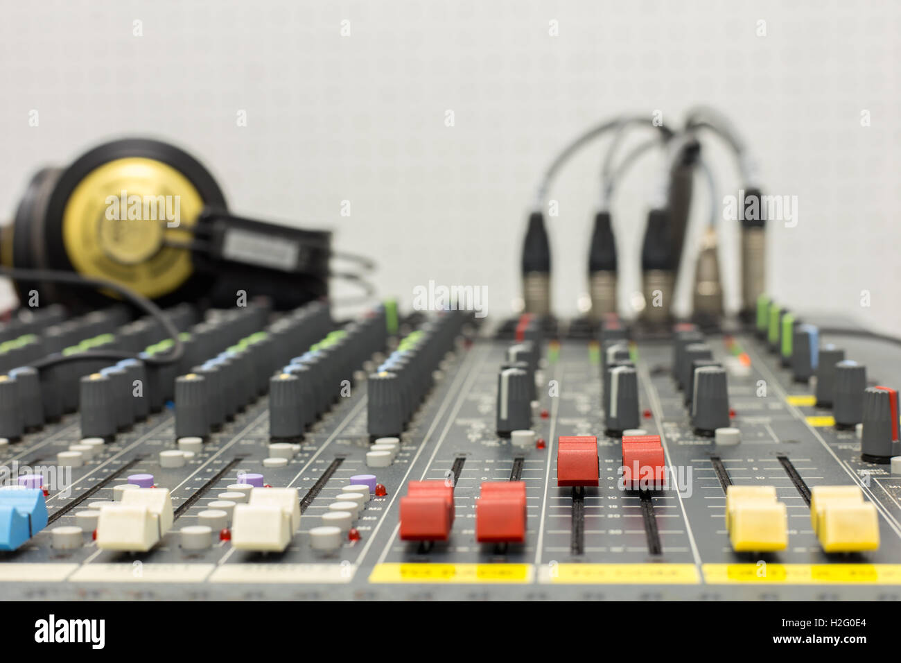 Photograph of a fader mixer red color, taken close up with a shallow depth of field. Background equipment and headphone. Stock Photo