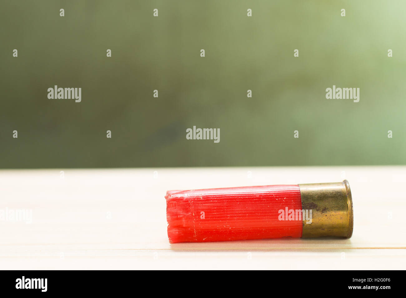 Through the use of shotgun shells lay on the wooden floor and green wall Background. Stock Photo