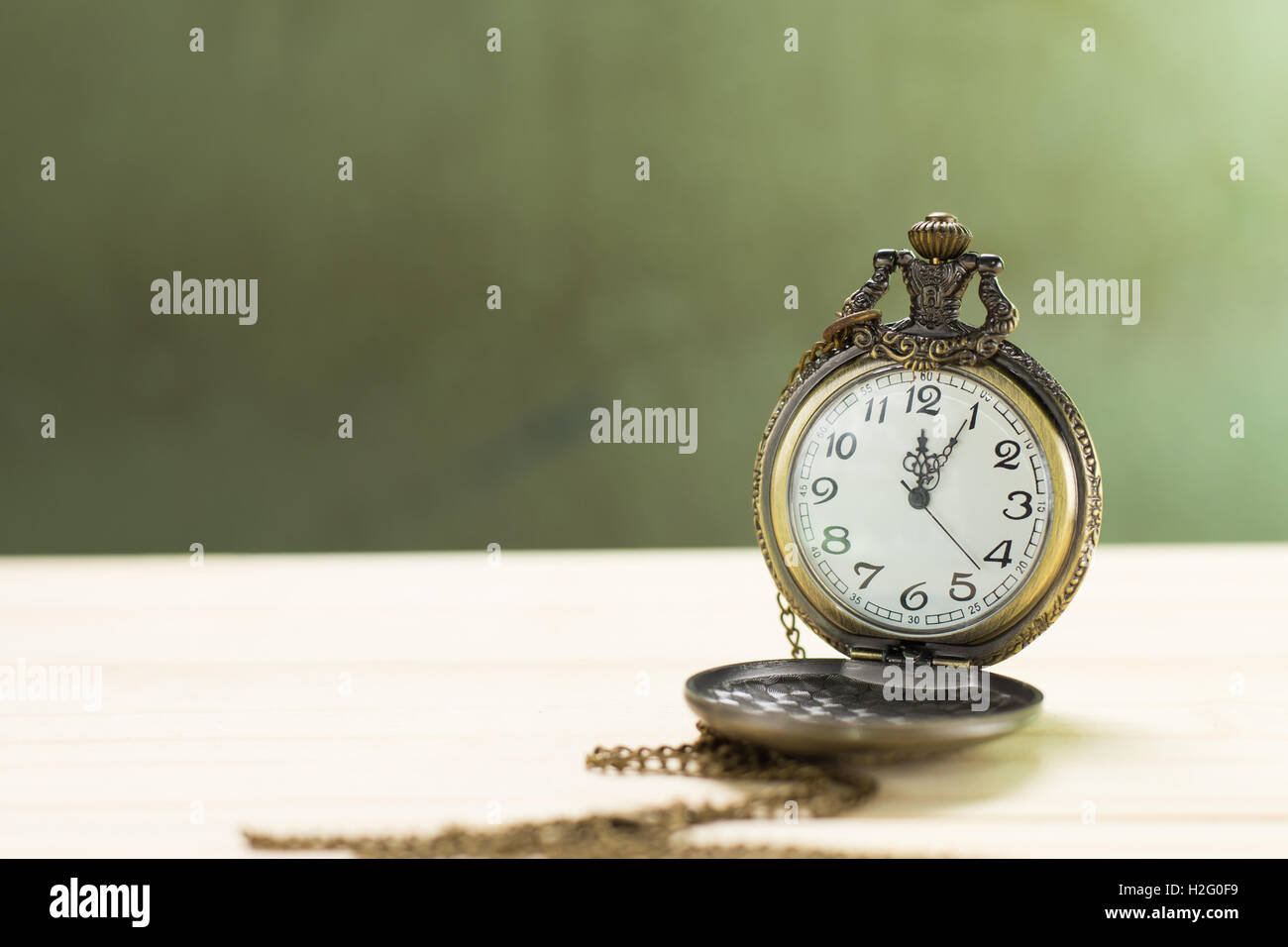 Antique clock on the wooden floor and green wall Background. Stock Photo