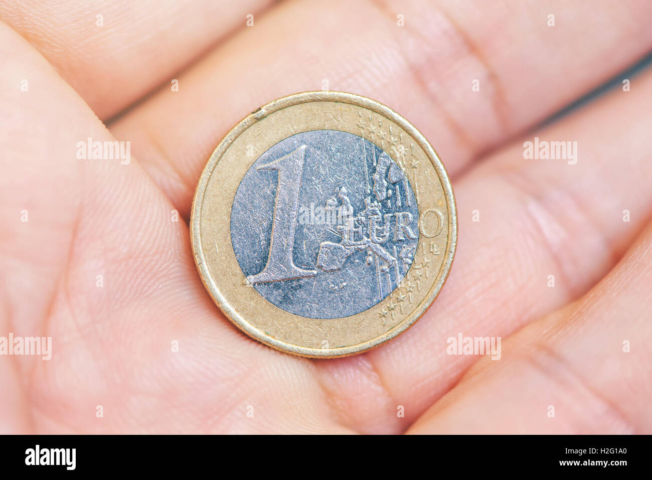 Man offering one euro coin on hand palm - business, finance, economy, funding, savings or money donation concept. Stock Photo