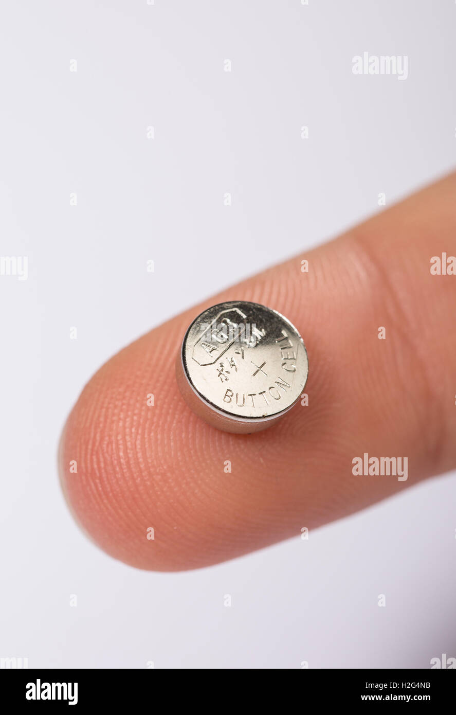 A child holding a button cell battery Stock Photo