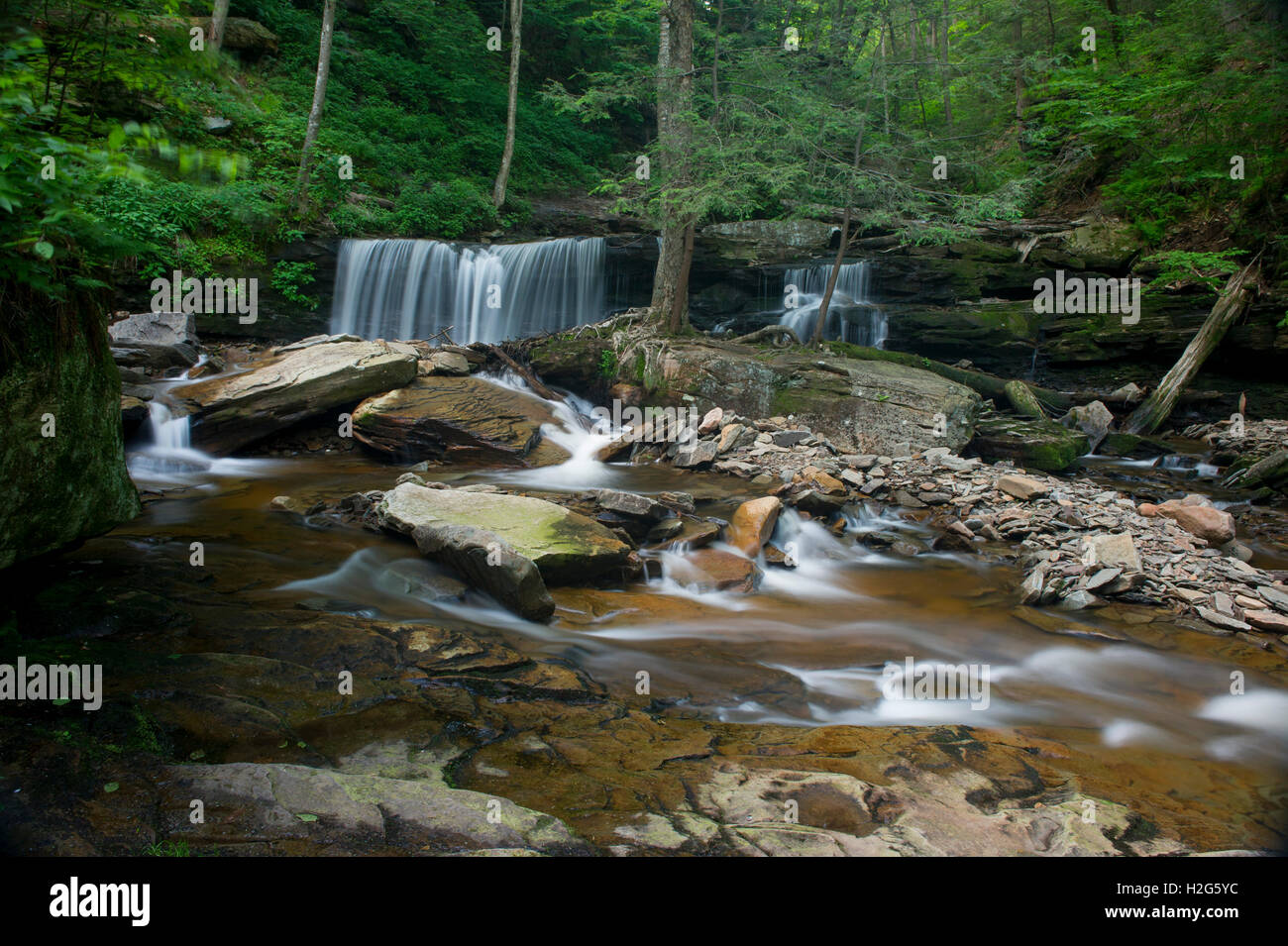 A long exposure of a scenic waterfall landscape in a bright green spring forest. Stock Photo