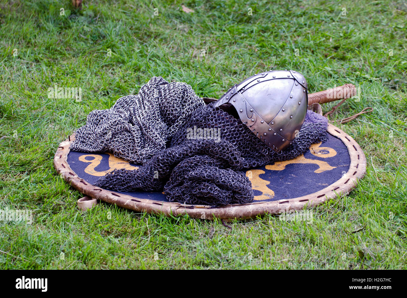 Knight armor headpiece placed on shield on grass at medieval festival Stock Photo