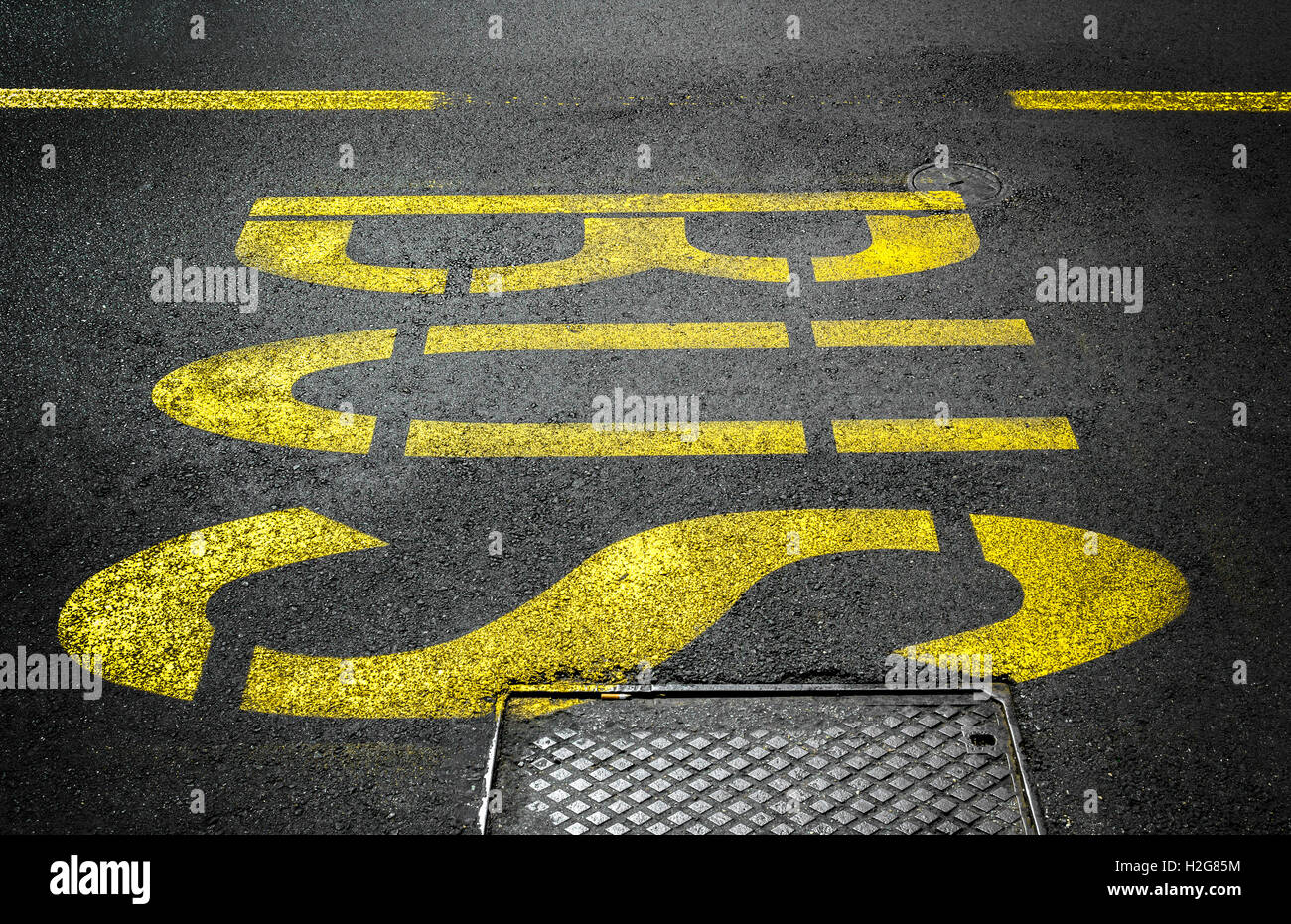 Yellow bus traffic sign painted on asphalt road. Stock Photo