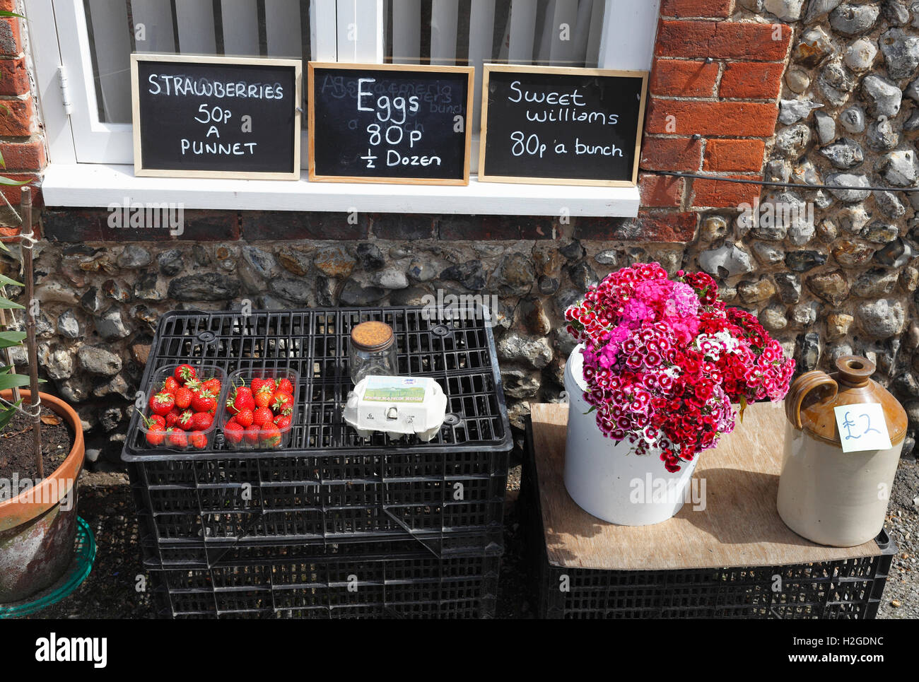 Strawberries, eggs and flowers for sale outside a cottage in Walsingham, Norfolk, England, UK. Stock Photo