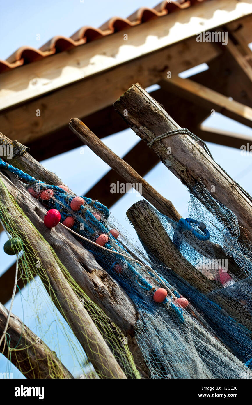 Fishing nets and buoys hanging on wooden stakes front of a fisherman's hut Stock Photo