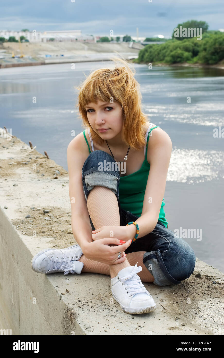 Young beautiful woman sitting on river bank Stock Photo - Alamy