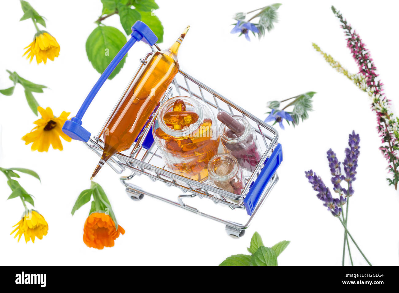 Shopping cart full of pharmaceutical drug and medicine pills over medicinal plants Stock Photo