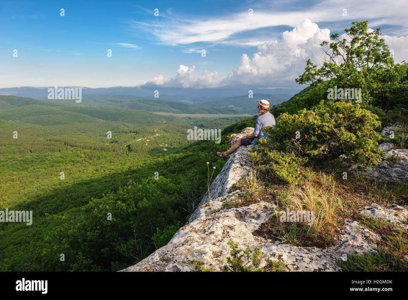 Hiking man in rays of sunset sitting at the edge Stock Photo