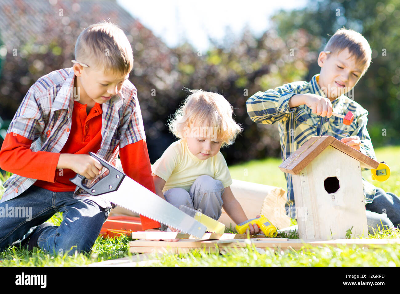 Children brothers making together nesting box outdoors Stock Photo
