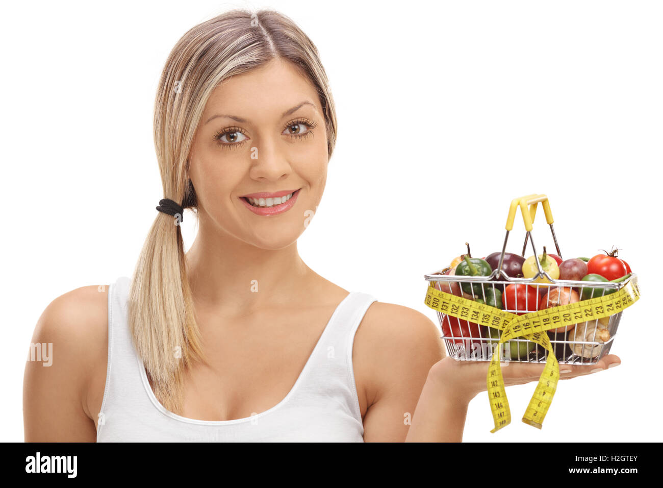 Woman holding a small shopping basket full of fruits and vegetables ...