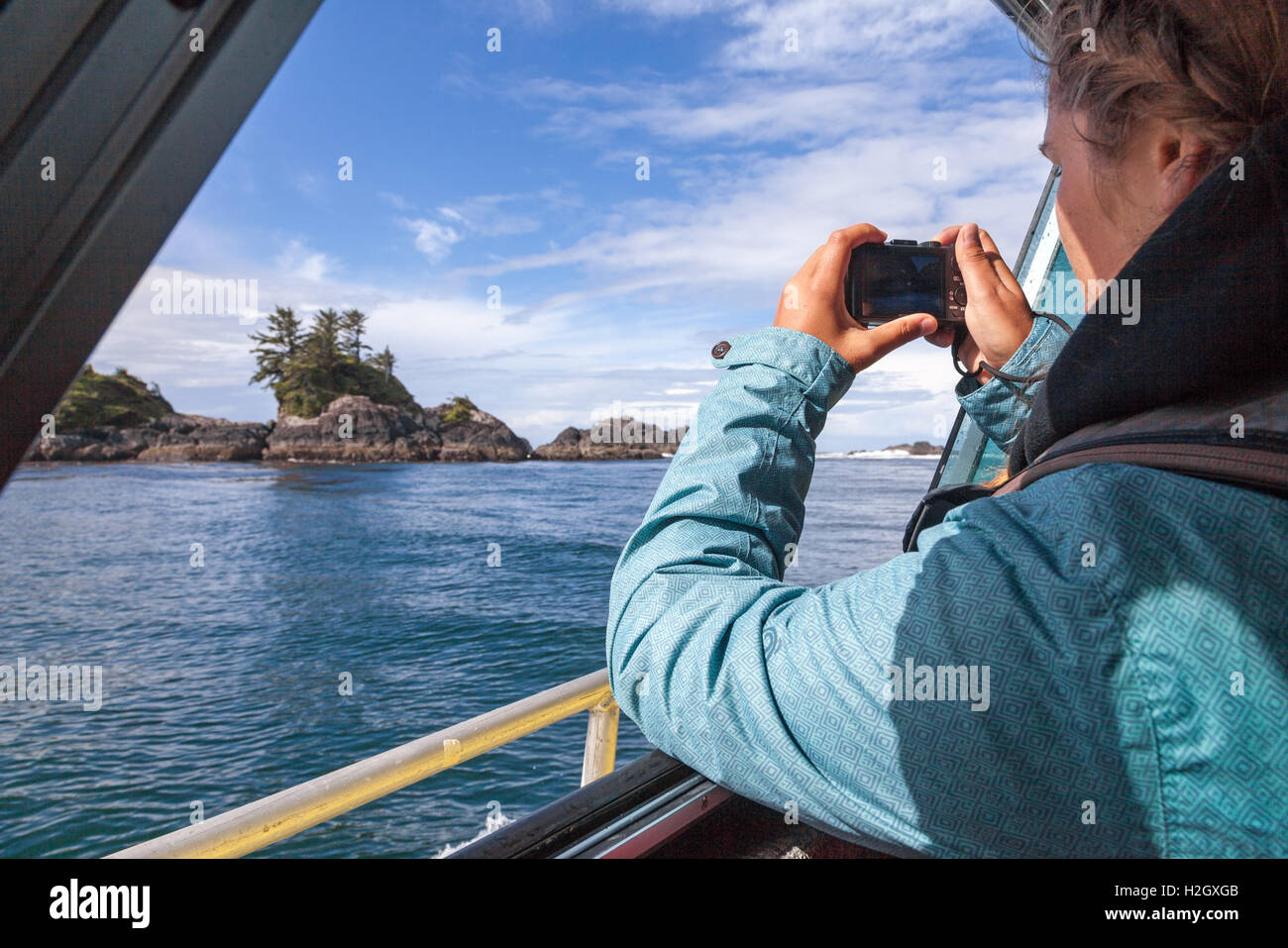 A woman on a boat taking a photograph on Ucluelet Peninsula on the west