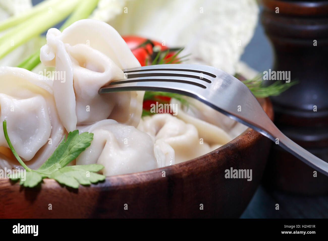 Closeup of fork near dish with ravioli and vegetables Stock Photo