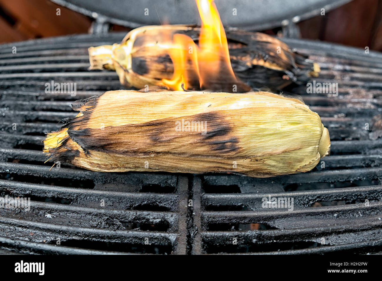 Corn cobs on the grill , flames coming of one of them. Stock Photo